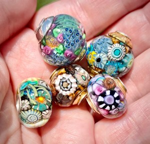 Handful of encased murrini beads with sterling silver cores and bead caps